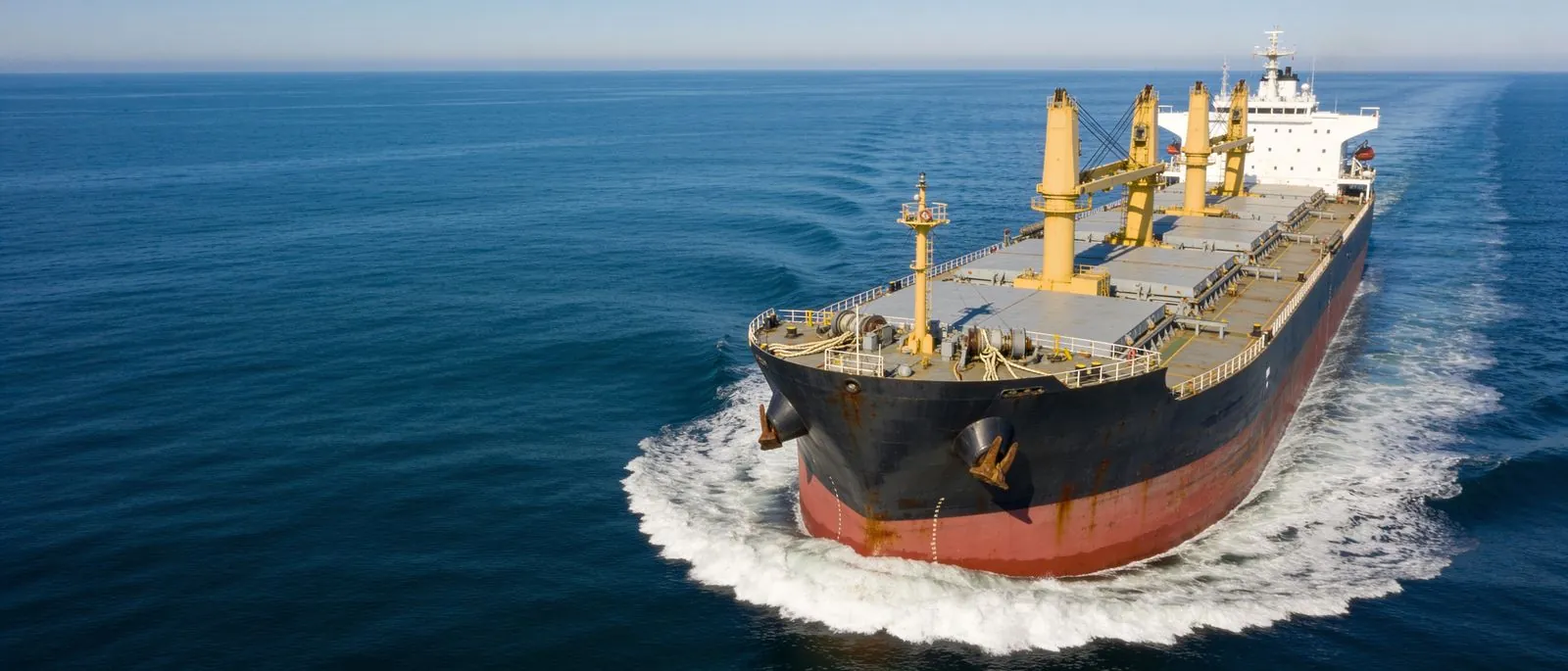 A loaded bulk carrier at anchor in open water.