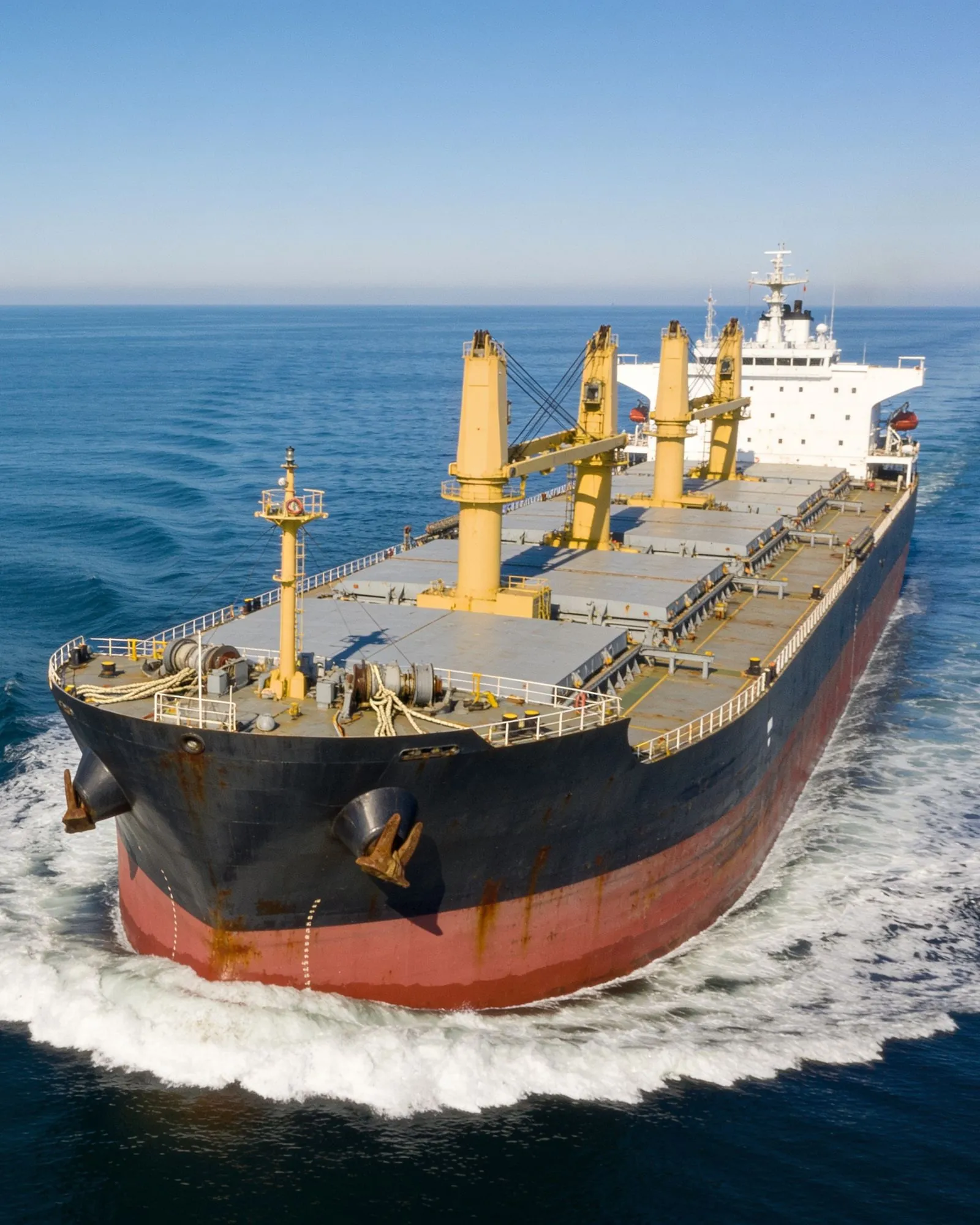 A loaded bulk carrier at anchor in open water.