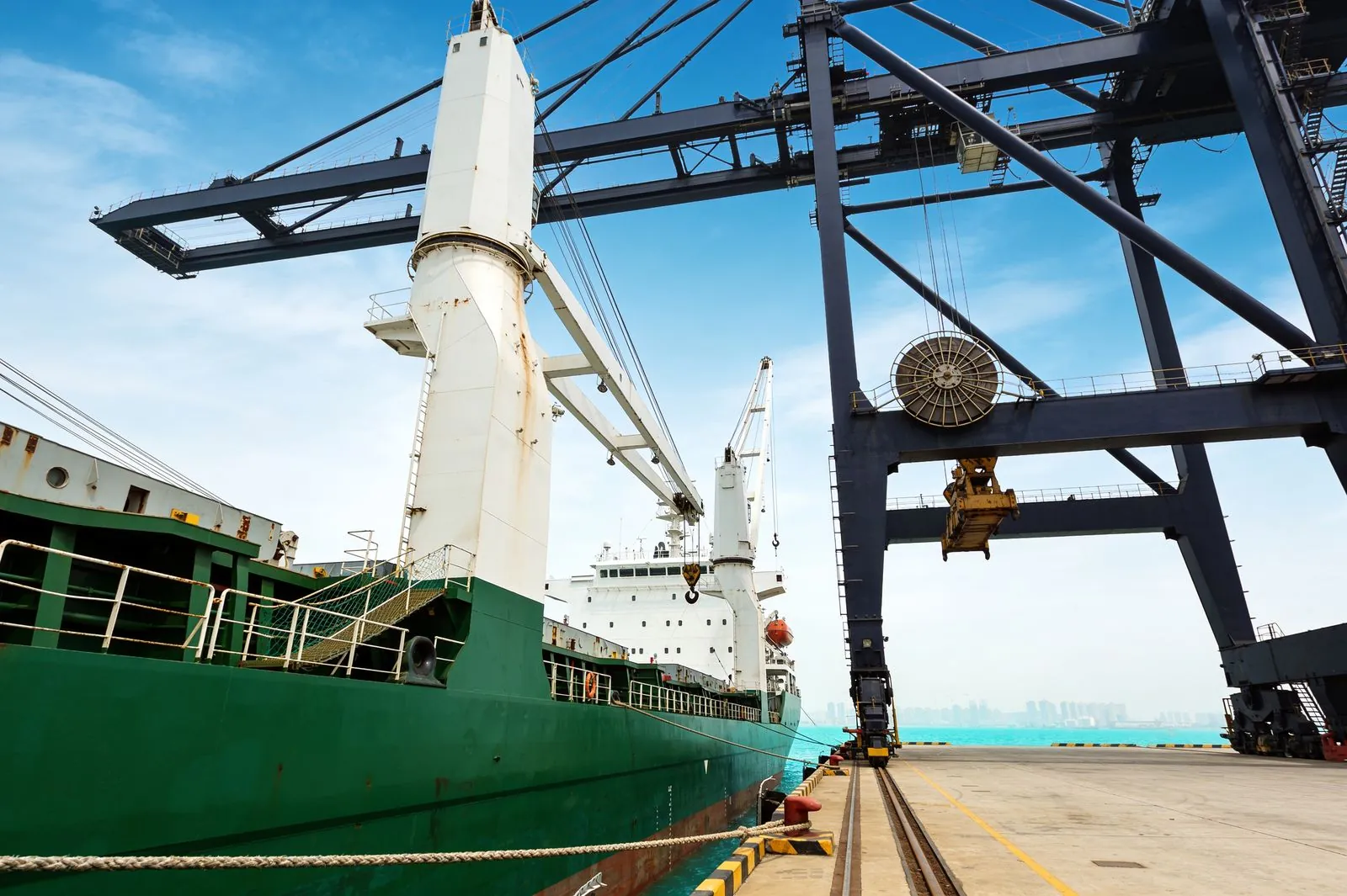 A heavy-lift vessel alongside, working under shore cranes.